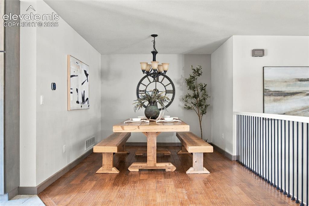 Image 8 of 37: Wood-finish flooring with a modern chandelier and a metal spindle railing