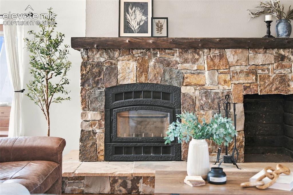 Image 9 of 37: Stone-faced fireplace with a substantial wood mantel and a metal firebox in