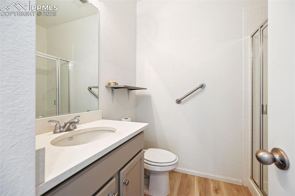 Image 10 of 24: Full bathroom with wood finished floors, a tile shower, and vanity