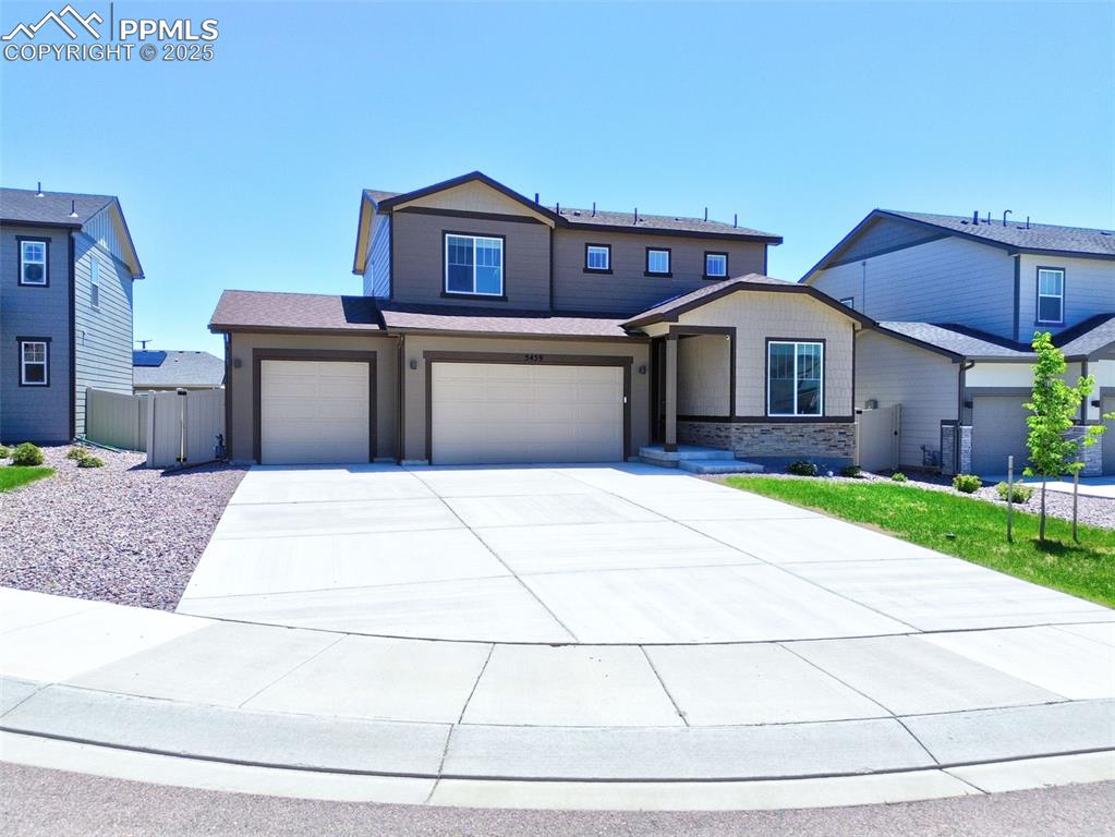 Image 2 of 24: View of front facade with driveway, a garage, and stone siding