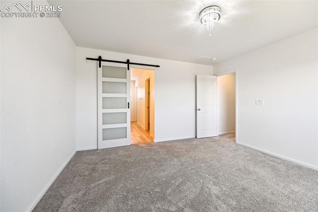 Image 20 of 24: Unfurnished bedroom featuring carpet flooring and a barn door