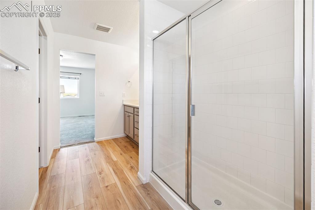 Image 22 of 24: Bathroom featuring vanity, wood finished floors, and a stall shower