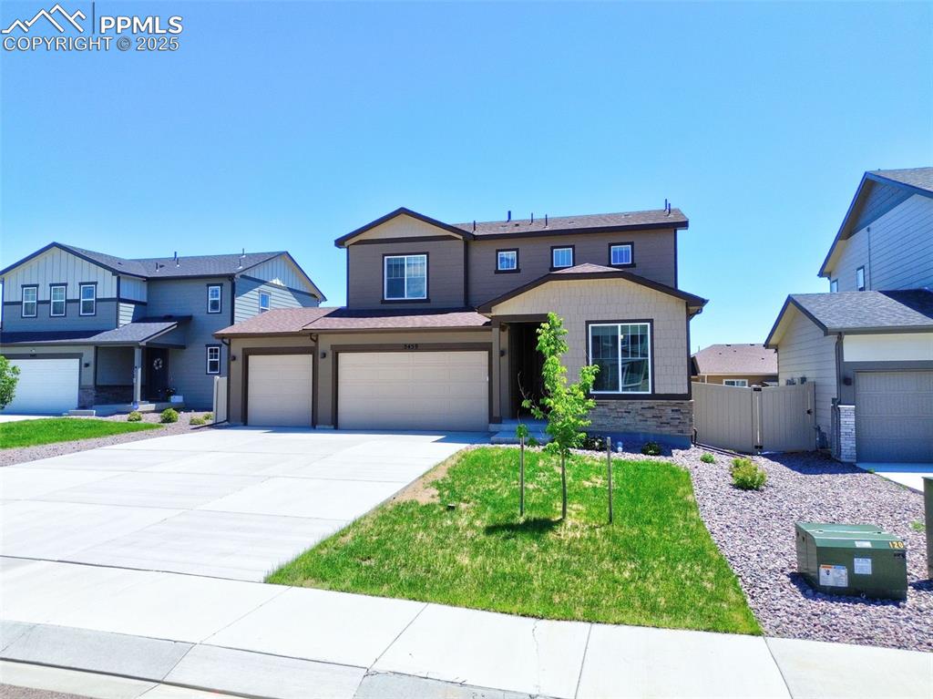 Image 3 of 24: View of front of home with concrete driveway, a garage, stone siding, and a