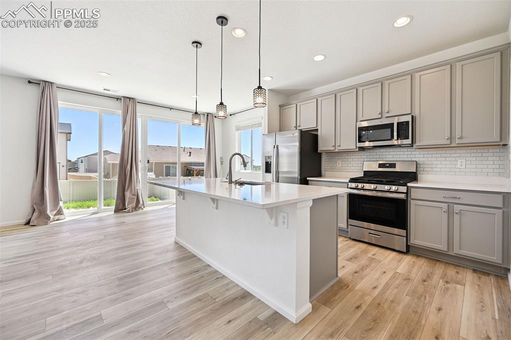 Image 4 of 24: Kitchen featuring appliances with stainless steel finishes, gray cabinetry,