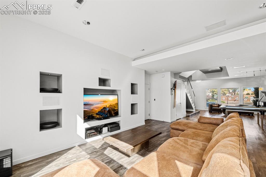 Image 11 of 41: Living area with built in features, wood finished floors, stairs, and reces