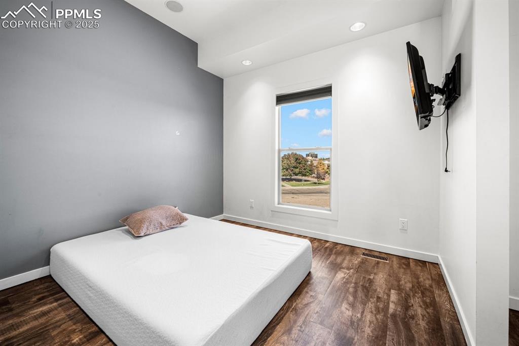 Image 18 of 41: Bedroom with dark wood-type flooring and recessed lighting