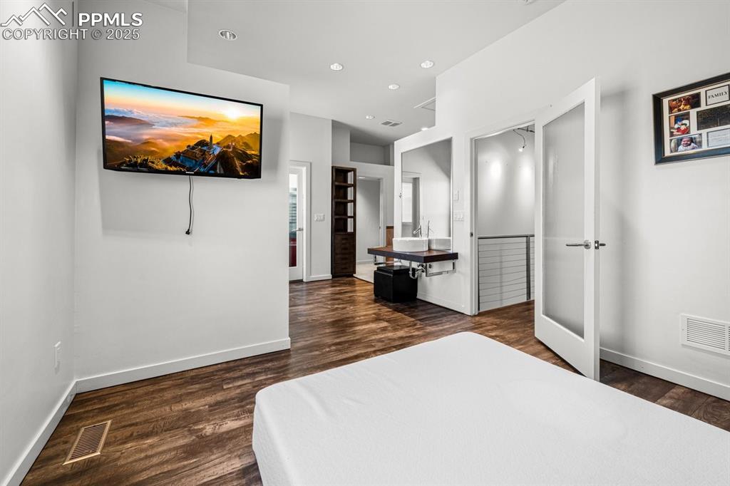Image 19 of 41: Bedroom with dark wood finished floors and recessed lighting