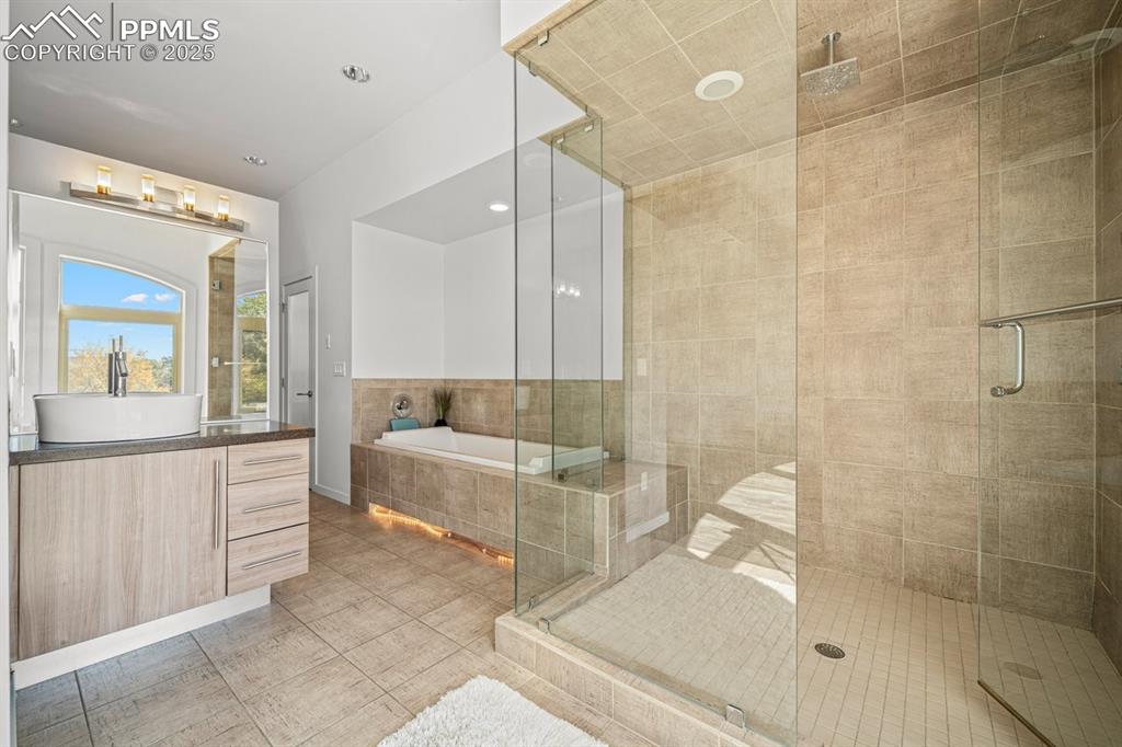 Image 26 of 41: Full bath featuring a garden tub, vanity, a shower stall, light tile patter