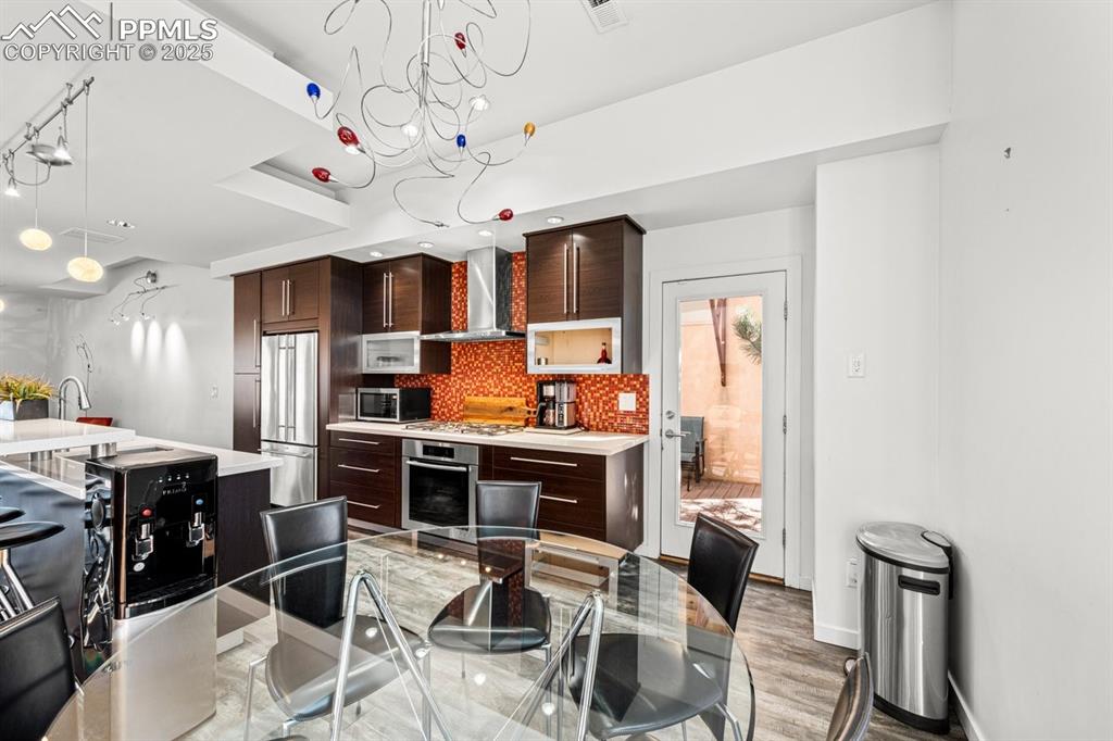 Image 30 of 41: Kitchen with tasteful backsplash, dark brown cabinetry, modern cabinets, an