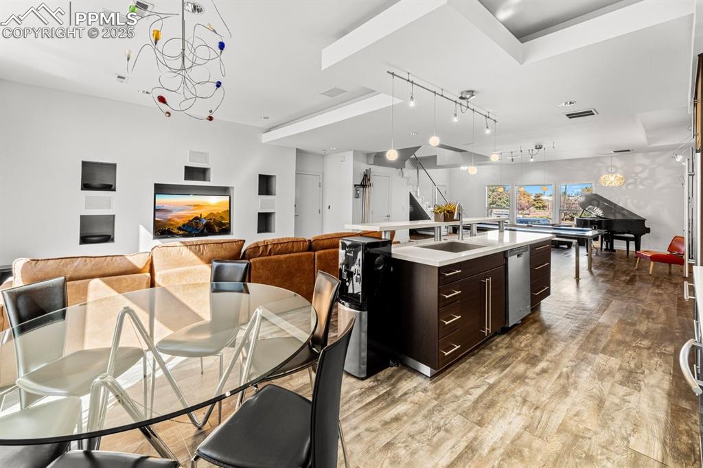 Image 9 of 41: Kitchen with dark brown cabinetry, open floor plan, decorative light fixtur