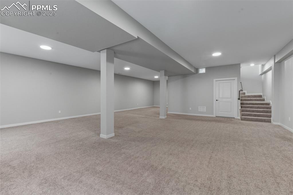 Image 30 of 50: Finished below grade area featuring light carpet, stairs, and recessed ligh