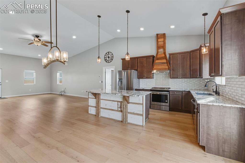 Image 9 of 50: Kitchen featuring light stone countertops, hanging light fixtures, applianc