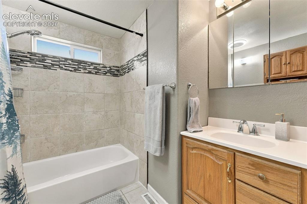 Image 10 of 48: Bathtub with tiled surround, decorative mosaic accent band, and an integrat