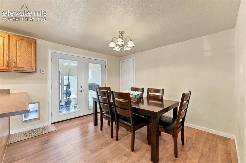 Image 17 of 48: Wood-finish flooring, white trim, and a white six-light chandelier