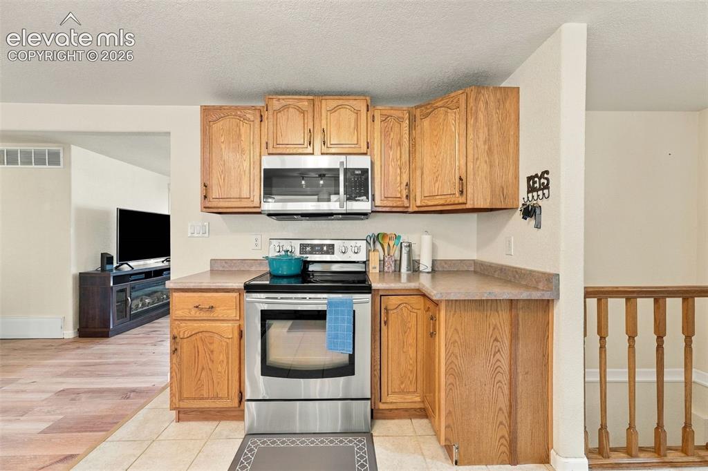 Image 20 of 48: Kitchen featuring wood cabinetry, stainless steel oven, stainless steel mic