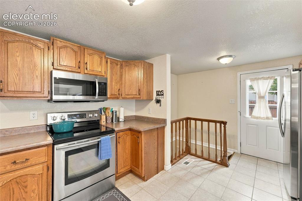 Image 22 of 48: Kitchen featuring wood-finish cabinetry, stainless steel appliances, durabl
