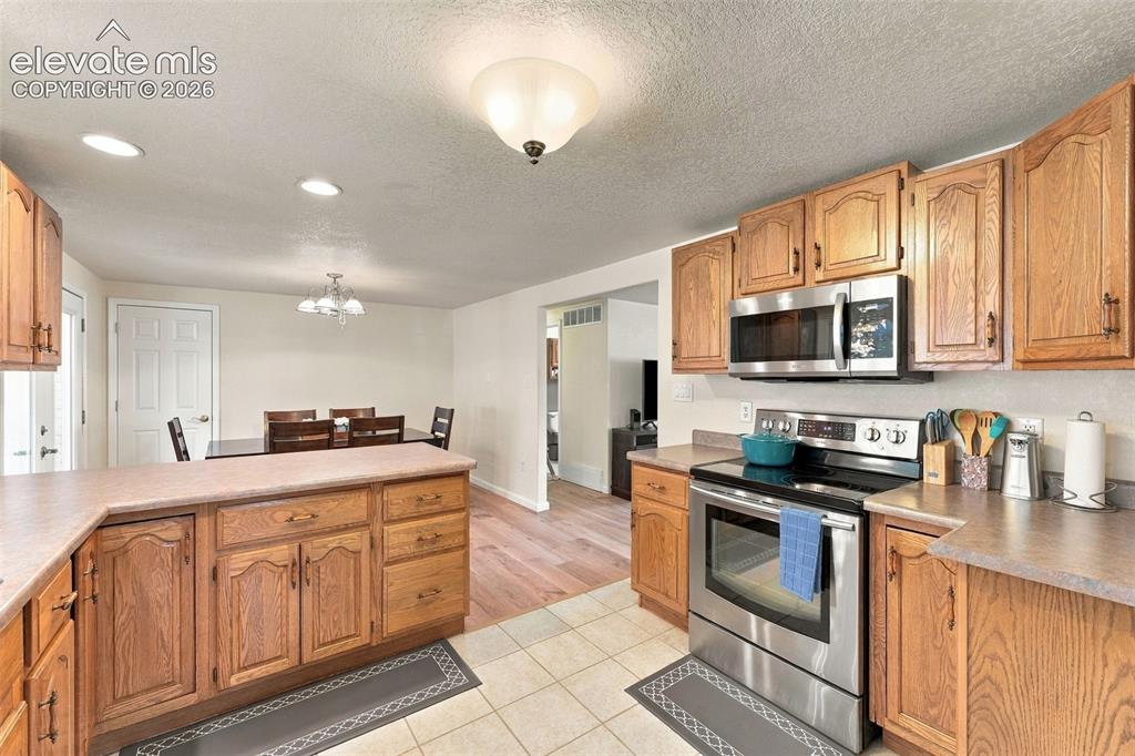 Image 23 of 48: Kitchen with wood-finish cabinetry, stainless steel appliances, and a built