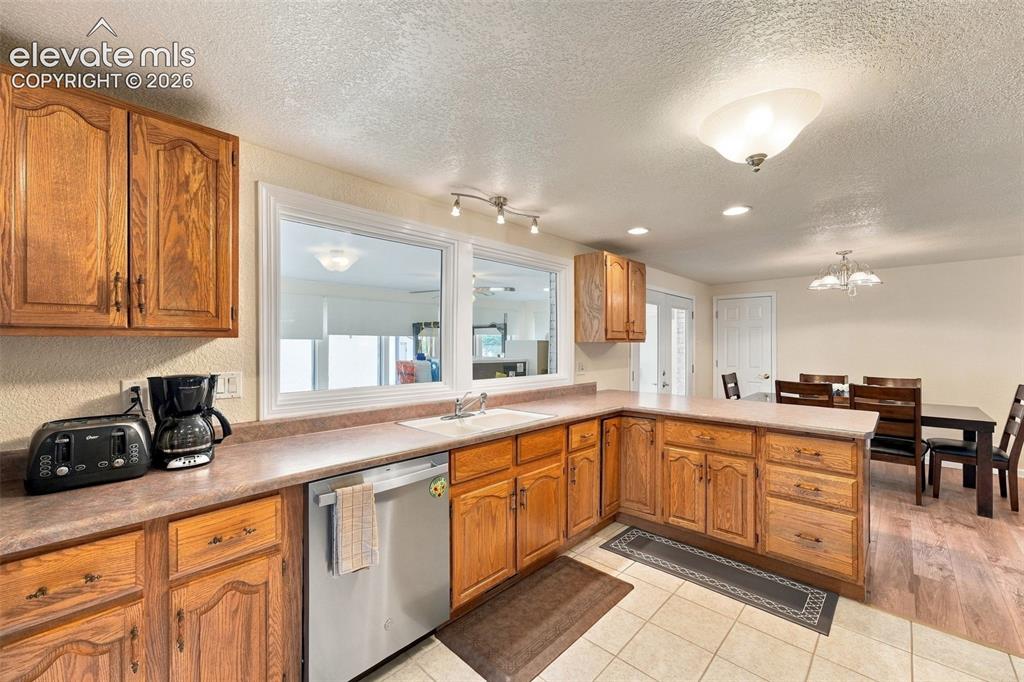 Image 24 of 48: Kitchen featuring wood cabinetry, a stainless steel dishwasher, an integrat