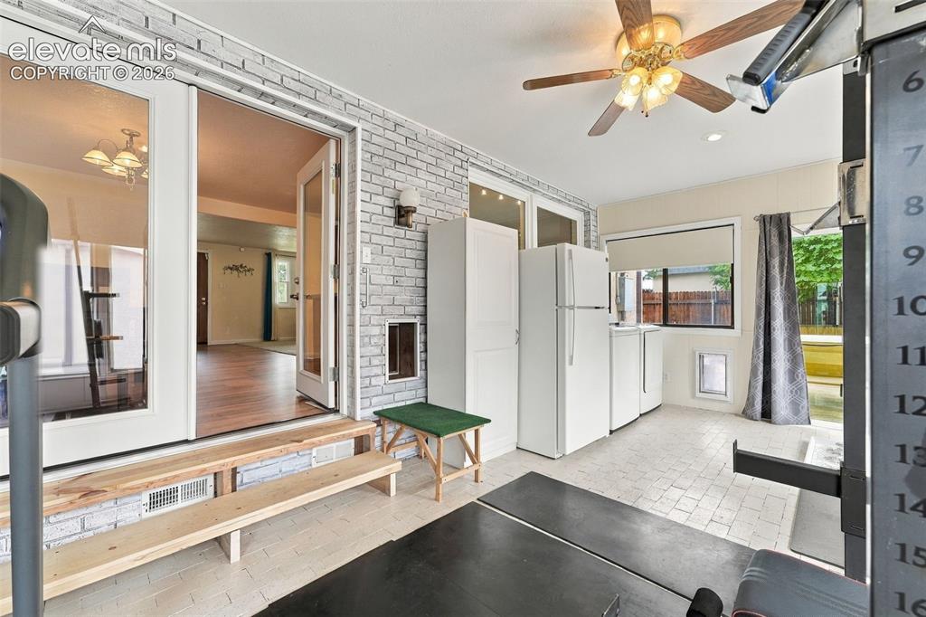Image 27 of 48: Sunroom with white brick-patterned walls, tiled flooring, and a ceiling fan