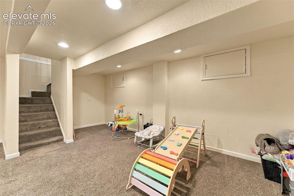 Image 30 of 48: Carpeted flooring, recessed lighting, white trim, and a window well cover