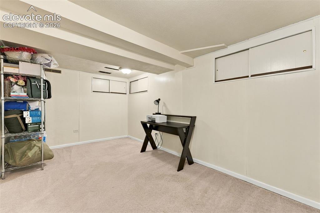Image 34 of 48: Carpeted flooring, painted walls, ceiling-mounted light fixture, exposed ce