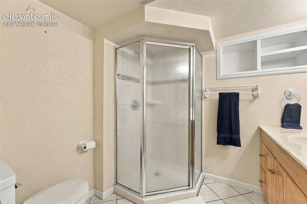 Image 36 of 48: Corner glass shower enclosure, wood-finish vanity with countertop, built-in