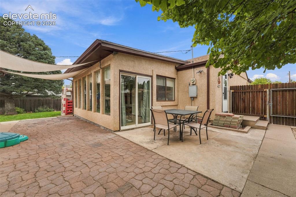 Image 37 of 48: Exterior featuring stucco siding, a paved patio, a sunroom with multiple wi