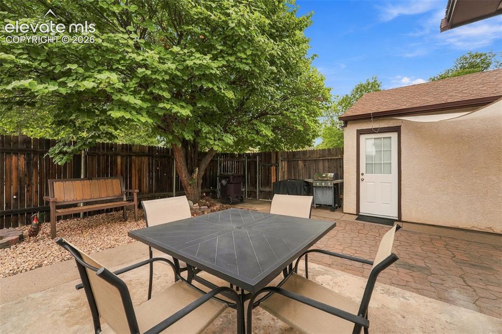 Image 38 of 48: Private backyard featuring a wood-panel fence, mature tree, concrete patio,