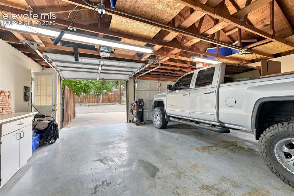 Image 39 of 48: Exposed wood ceiling beams, fluorescent overhead lighting, concrete floorin
