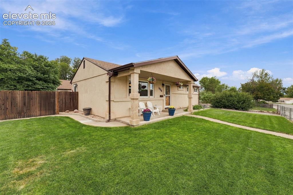 Image 4 of 48: Stucco exterior with a covered porch, concrete walkway, and a wooden fence