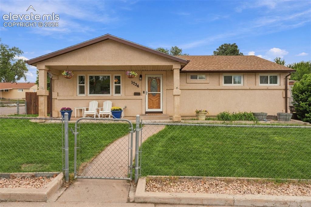 Image 5 of 48: Stucco exterior with a covered front porch, a chain-link fence, and a grave