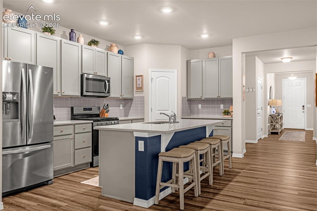 Image 13 of 40: Kitchen featuring light gray cabinetry, stainless steel appliances, a cente