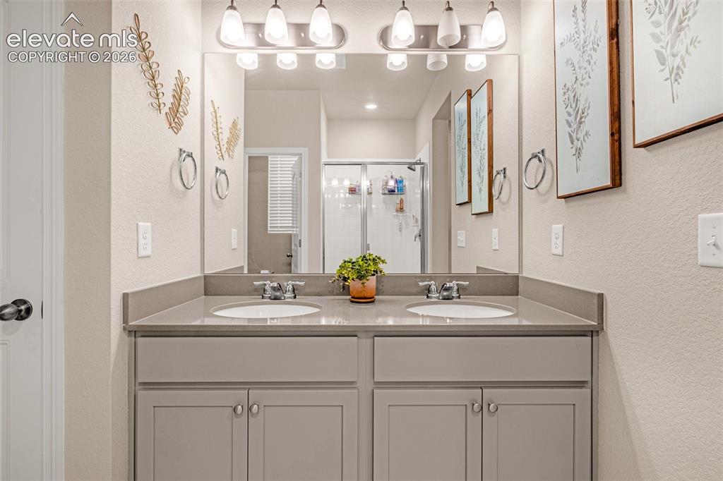 Image 21 of 40: Dual vanity with undermount sinks, gray cabinetry, and a spacious counterto