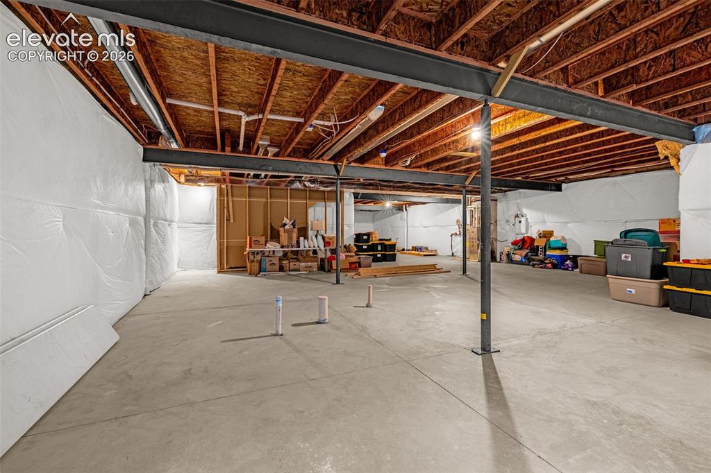 Image 28 of 40: Unfinished basement with concrete flooring and exposed ceiling joists