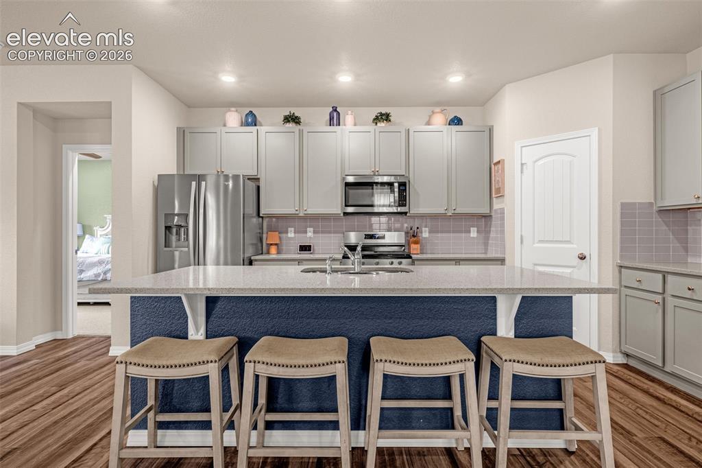 Image 3 of 40: Kitchen featuring an expansive island with a light-toned countertop, gray s