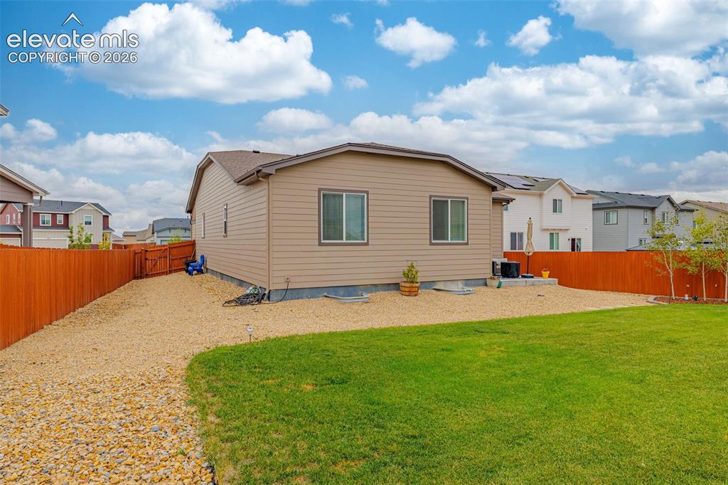 Image 30 of 40: Expansive backyard featuring a manicured lawn, gravel patio, and wood priva