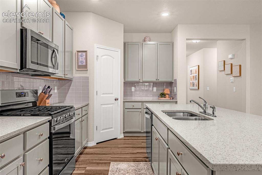 Image 5 of 40: Kitchen featuring light gray cabinetry, stainless steel appliances, wood-fi