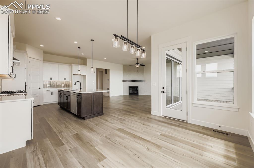Image 12 of 29: Kitchen with light countertops, ceiling fan, light wood-style flooring, whi