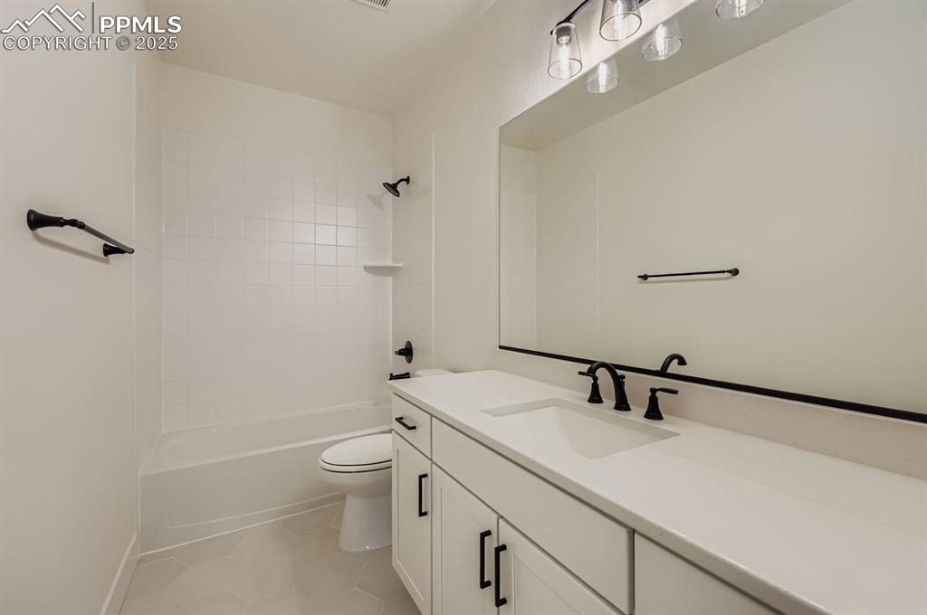 Image 24 of 29: Bathroom featuring vanity, shower / tub combination, and tile patterned flo