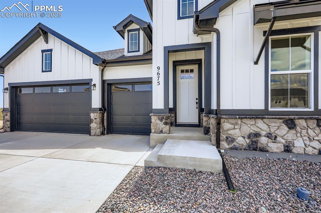 Image 4 of 29: View of exterior entry featuring board and batten siding, driveway, an atta