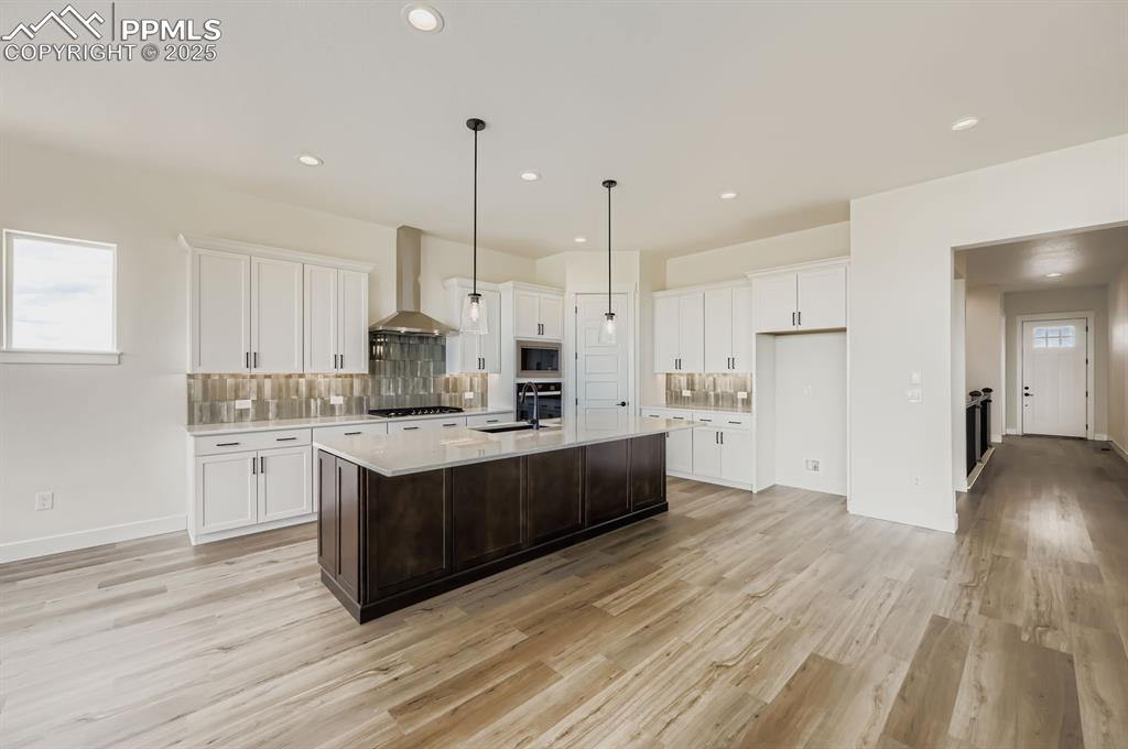 Image 9 of 29: Kitchen with light countertops, light wood finished floors, white cabinetry