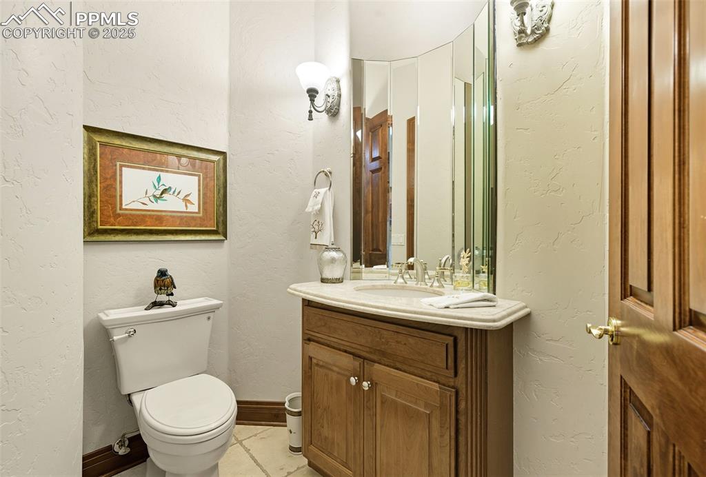 Image 25 of 50: powder room with a curved mirror and luxurious countertop.