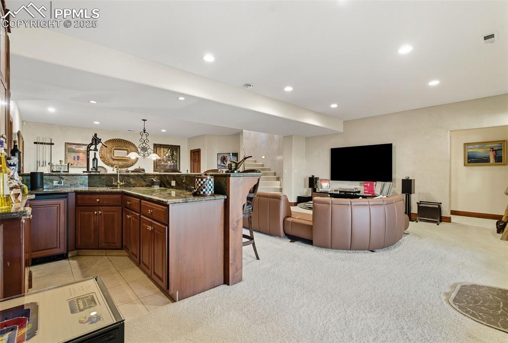 Image 38 of 50: large wet bar with custom Verde Fuoco granite tops.