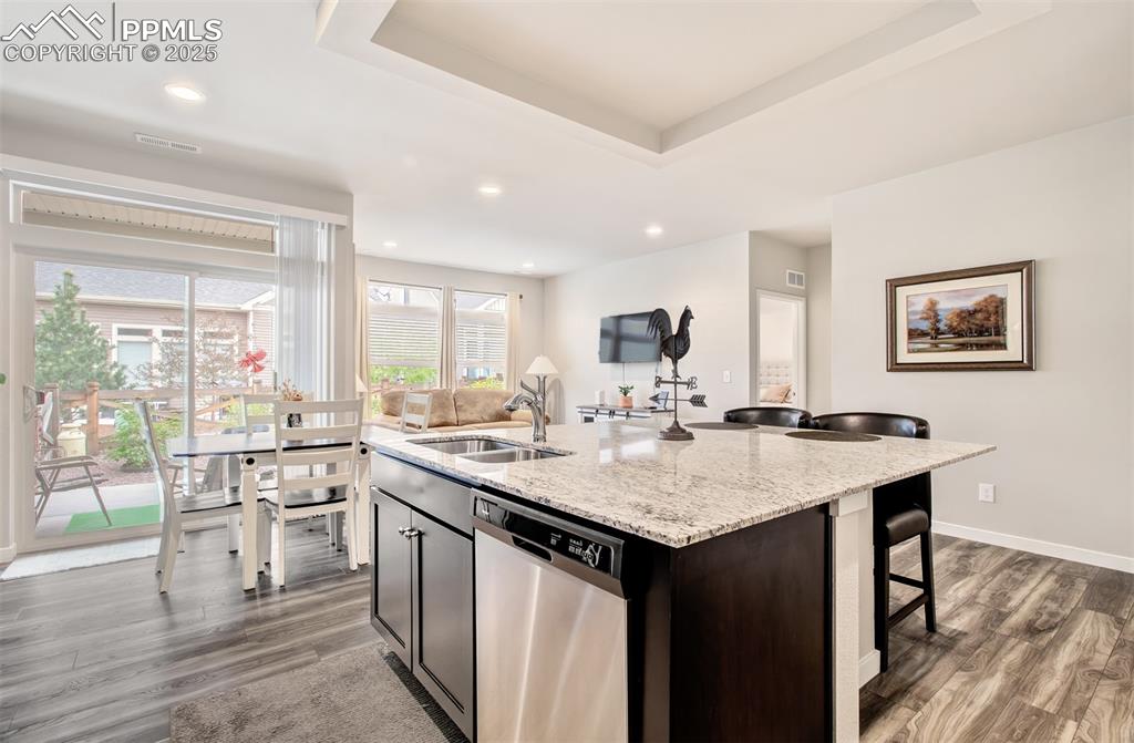 Image 13 of 39: Kitchen featuring stainless steel dishwasher, a sink, dark wood finished fl