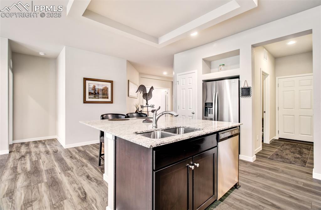 Image 16 of 39: Kitchen with stainless steel appliances, a sink, a breakfast bar, baseboard