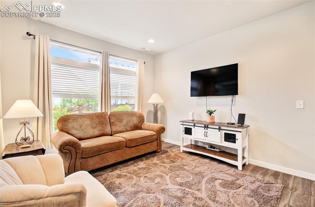 Image 18 of 39: Living room featuring wood finished floors, baseboards, and recessed lighti