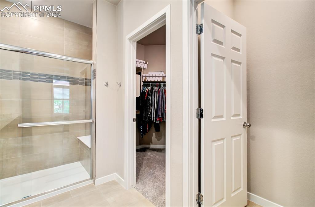 Image 25 of 39: Full bath with a shower stall, a walk-in closet.