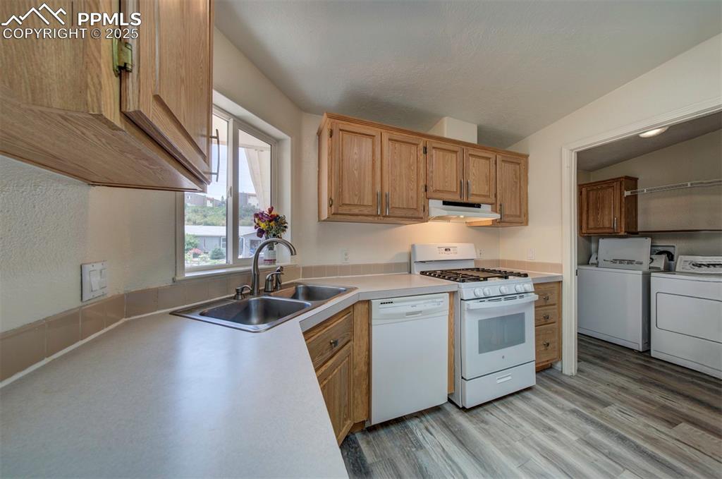 Image 13 of 31: Kitchen with white appliances, under cabinet range hood, washing machine an