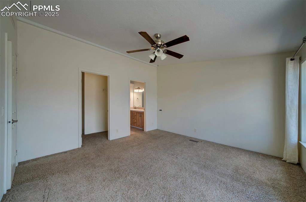 Image 17 of 31: Unfurnished bedroom with carpet, a ceiling fan, and connected bathroom