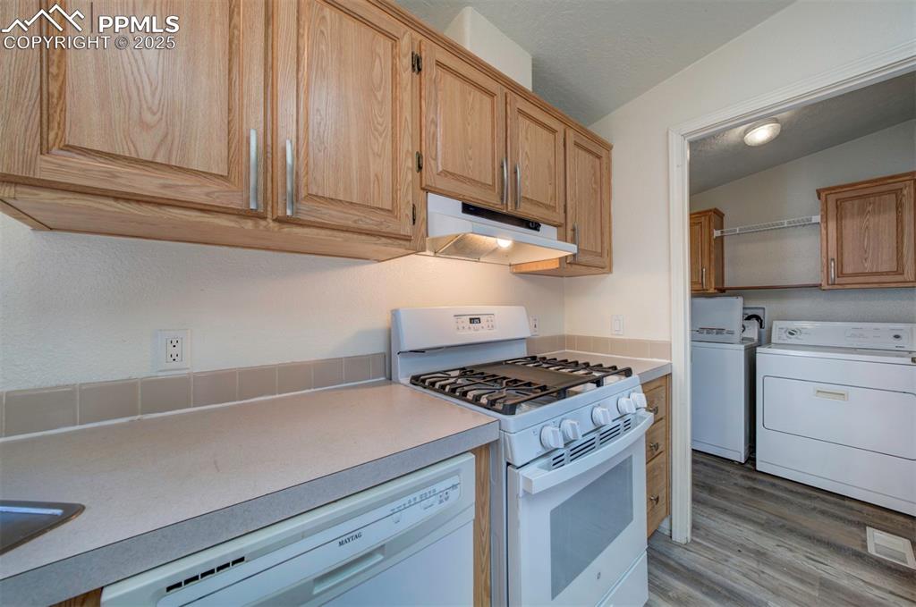Image 22 of 31: Kitchen featuring white appliances, under cabinet range hood, washer and dr